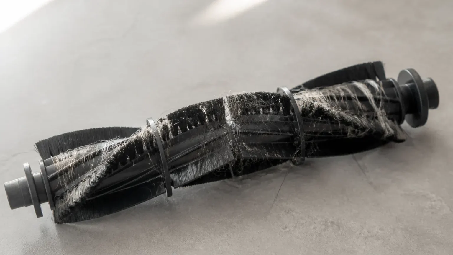 Gros plan sur une brosse de robot aspirateur emmêlée de poils d'animaux